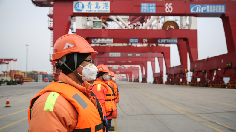 Workers at the port of Qingdao wearing anti-coronavirus masks STR/AFP via Getty Images