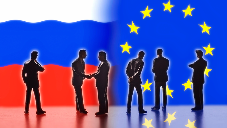  Model figures symbolizing politicians are facing the flags of Russia and the EU. Two of them shake hands. - Image ID: EA25YH 