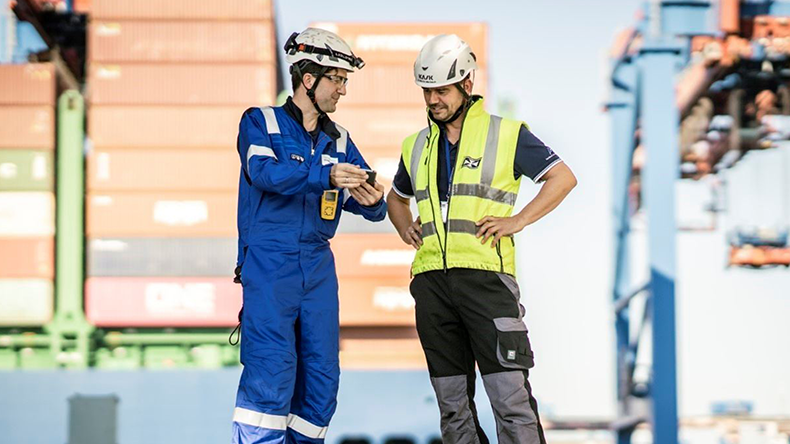 Two maritime seafarers discuss safety at a port