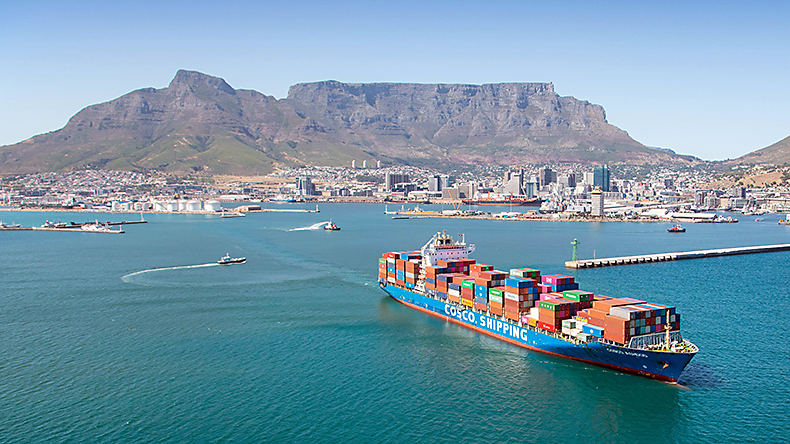 Aerial photo of a containership with tugs and Table Mountain in background
