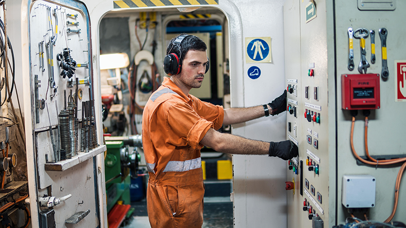 Marine engineer officer controlling vessel engines in engine control room