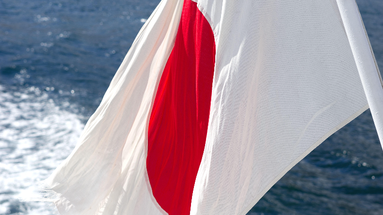 Japanese flag hanging at the back of a ship with sea in background