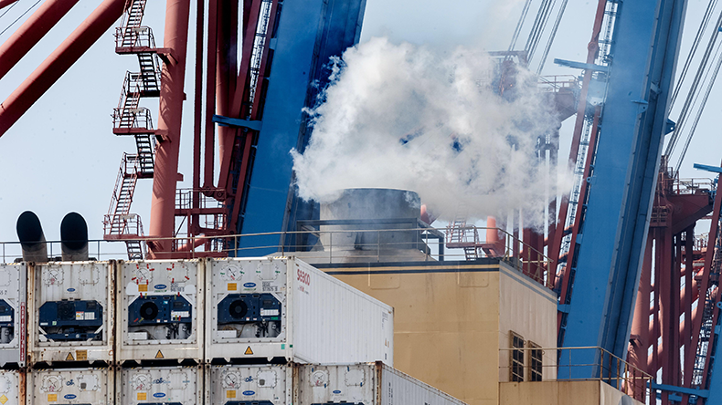 Exhaust gases come out of the smokestack of a containership while it is docked