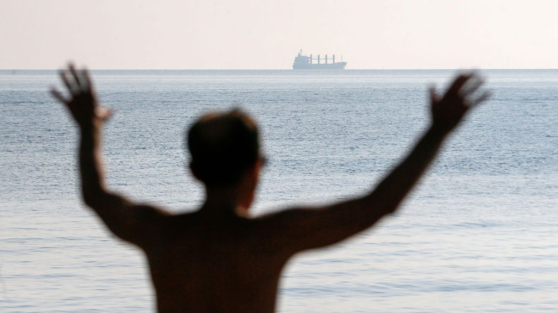 Man doing yoga at Odesa as grain ship departs